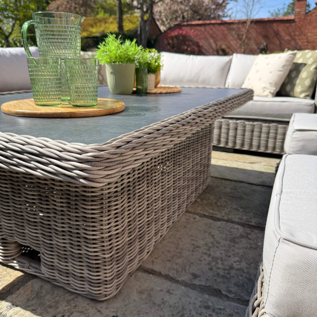 Outdoor patio setting with wicker table and chairs on a sunny day.