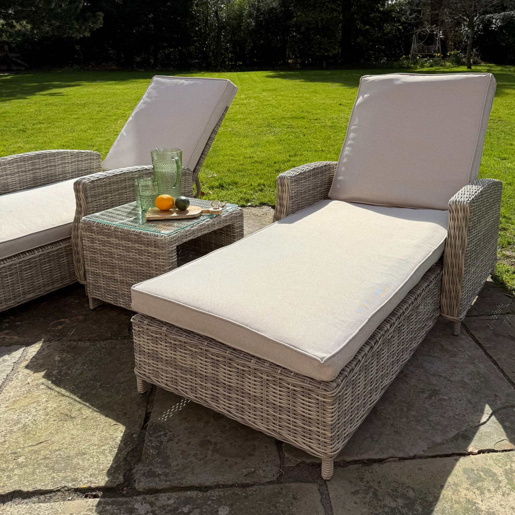 Sienna Twin Sun Lounger Set with cream cushions and glass top side table in natural rattan weave outdoors